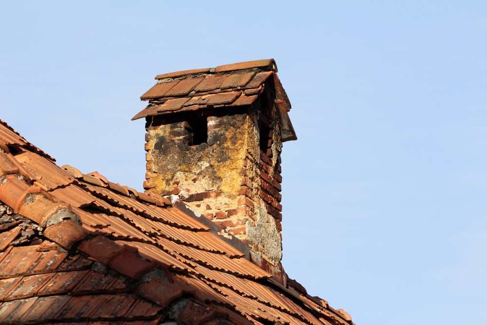 A,Brick,Chimney,Crowned,With,A,Tiled,Cap,Shows,Heavy