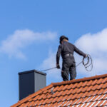 Chimney,Sweep,Cleaning,A,Chimney,Standing,On,The,House,Roof,