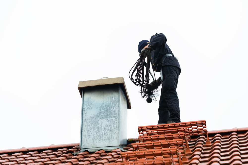 Chimney,Sweep,Standing,On,Roof,Of,Home,Working