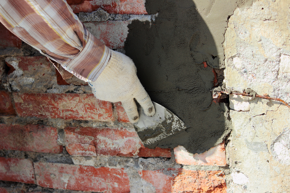 A,Professional,Builder,Bricklayer,With,Hand,Trowel,Applies,Cement,Mortar